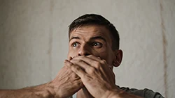 Мужчина закрывает рот руками